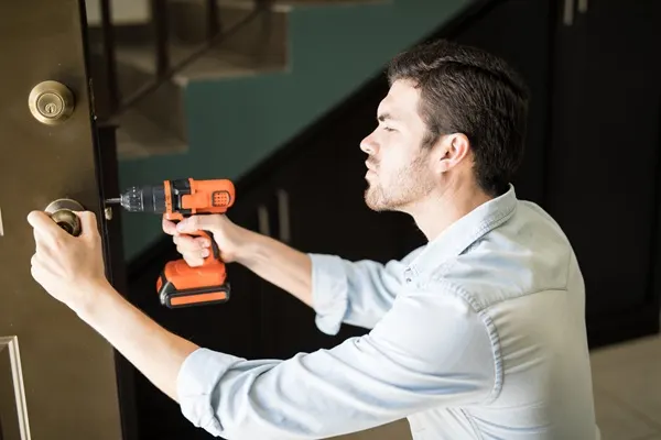 profile-view-attractive-handyman-using-power-drill-fix-door-knob-house